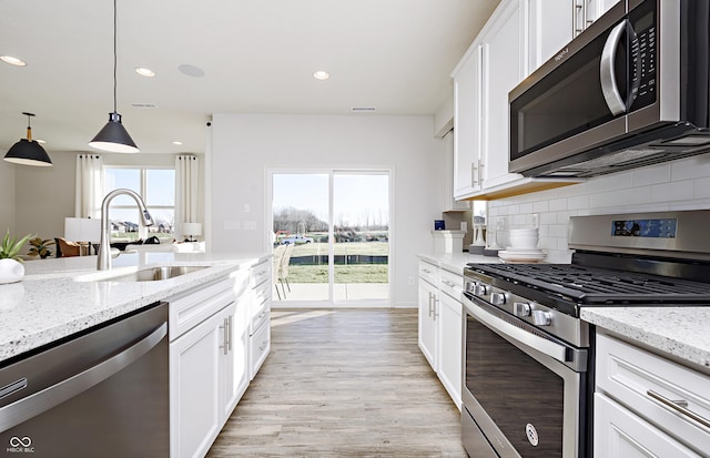 kitchen featuring white cabinetry, sink, pendant lighting, and appliances with stainless steel finishes