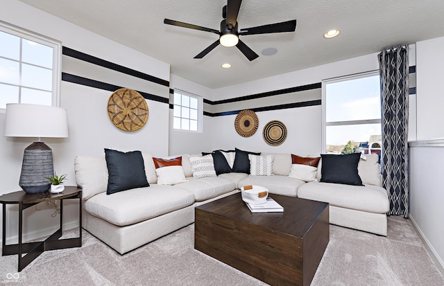 living room featuring light carpet, a textured ceiling, and ceiling fan