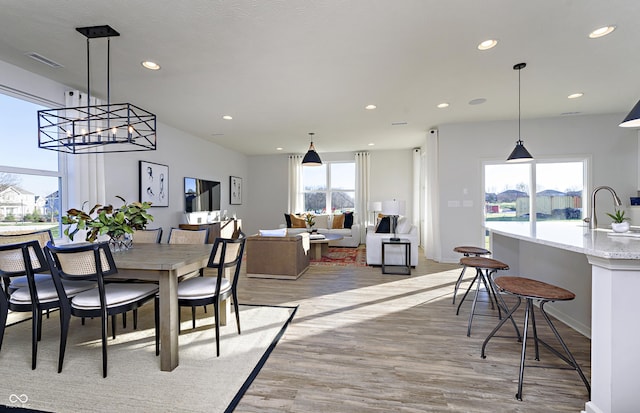 dining space with sink, an inviting chandelier, and light wood-type flooring