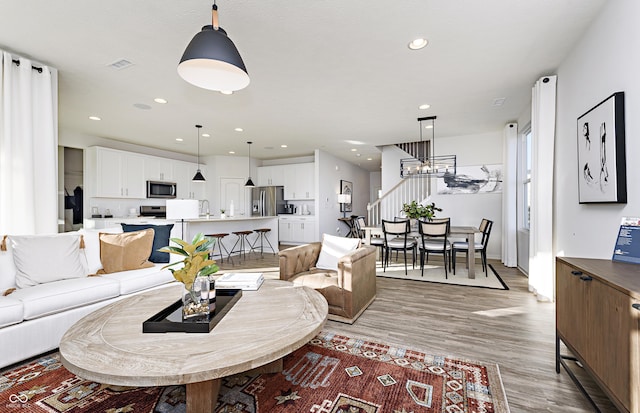 living room featuring a chandelier, wood-type flooring, and sink