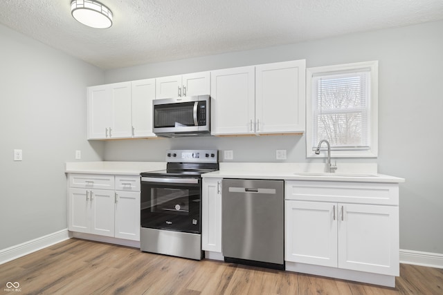 kitchen with stainless steel appliances, light hardwood / wood-style floors, sink, and white cabinets