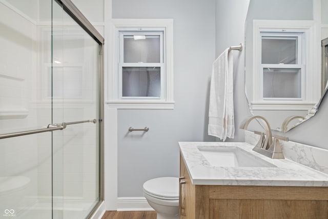 bathroom featuring vanity, a shower with shower door, hardwood / wood-style floors, and toilet