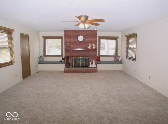 unfurnished living room with a brick fireplace, carpet, a wealth of natural light, and ceiling fan