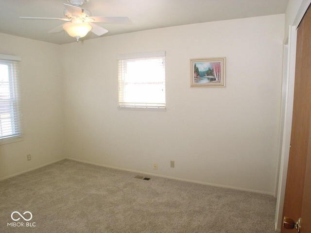 carpeted empty room with ceiling fan and a wealth of natural light