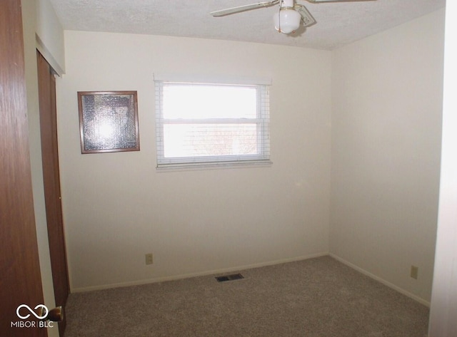 spare room with a textured ceiling, ceiling fan, and carpet