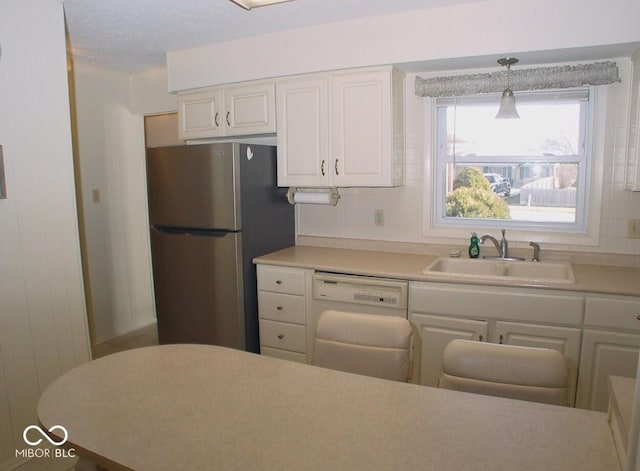 kitchen featuring dishwasher, white cabinetry, sink, hanging light fixtures, and stainless steel refrigerator