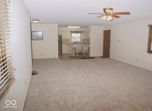 unfurnished living room with ceiling fan and light colored carpet