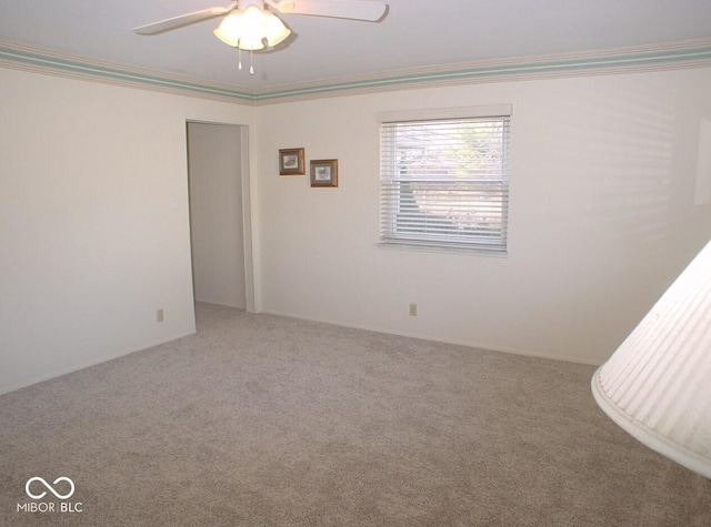 carpeted spare room featuring ceiling fan and crown molding