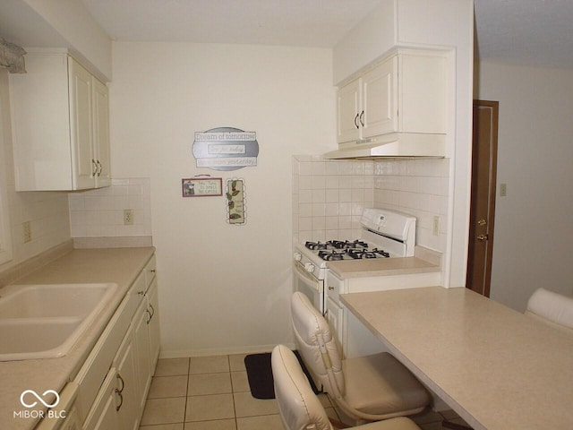 kitchen featuring tasteful backsplash, light tile patterned floors, sink, and gas range gas stove