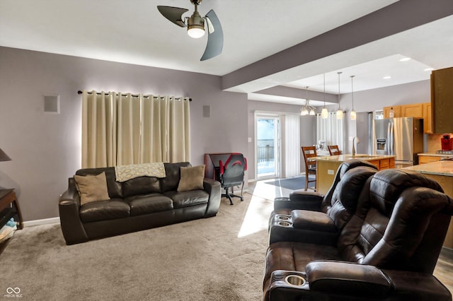 carpeted living room with a raised ceiling, sink, and ceiling fan