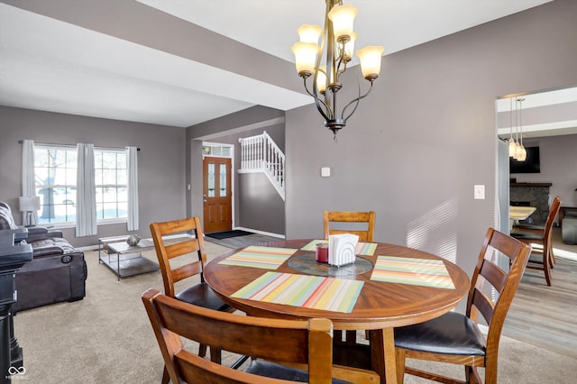 carpeted dining space with a fireplace and an inviting chandelier