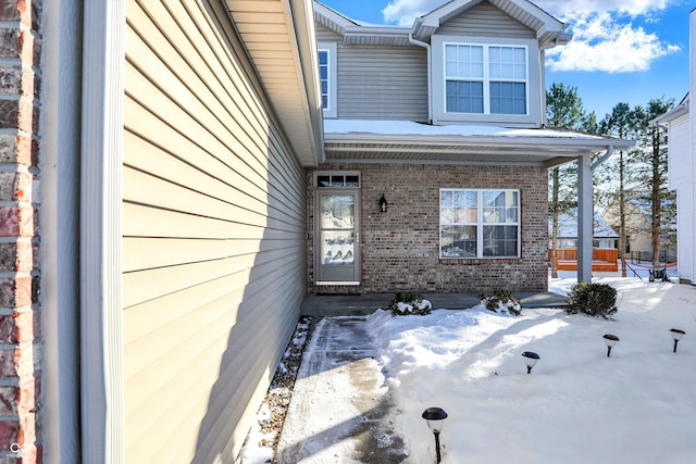 snow covered property entrance with a porch