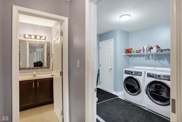 clothes washing area with washer and clothes dryer, sink, and a textured ceiling