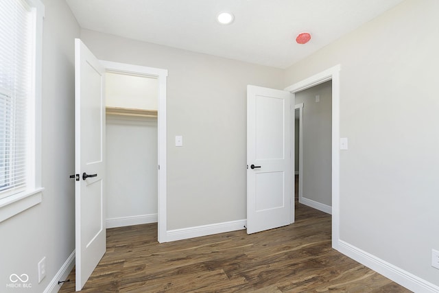 unfurnished bedroom featuring dark hardwood / wood-style floors, a spacious closet, and a closet