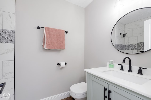 bathroom featuring vanity, toilet, and a tile shower