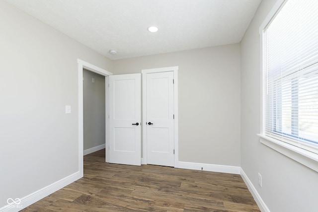 unfurnished bedroom with dark hardwood / wood-style floors and a closet