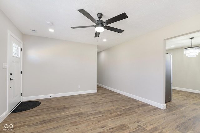 spare room featuring a textured ceiling, dark hardwood / wood-style flooring, and ceiling fan with notable chandelier