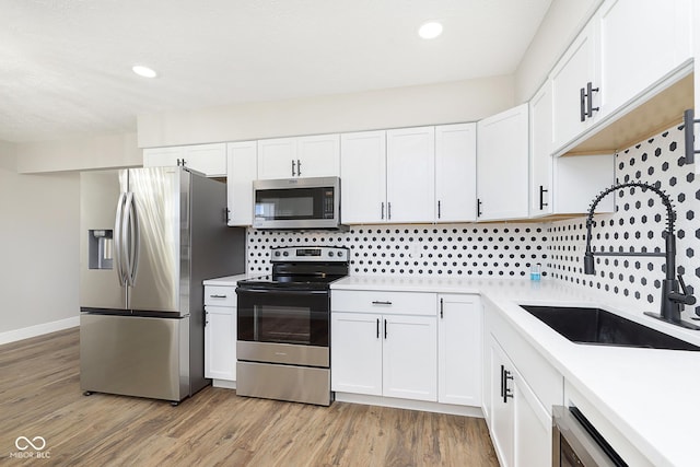 kitchen featuring sink, white cabinets, stainless steel appliances, and light hardwood / wood-style floors