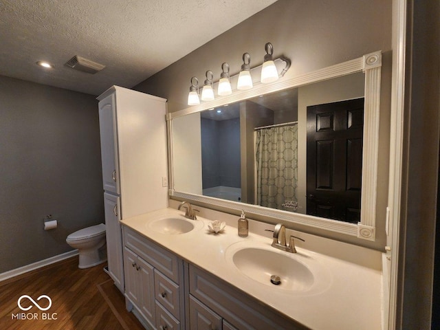 bathroom featuring vanity, a shower with curtain, hardwood / wood-style flooring, toilet, and a textured ceiling