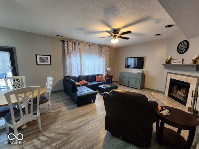 living room with a wealth of natural light, a fireplace, light hardwood / wood-style floors, and a textured ceiling