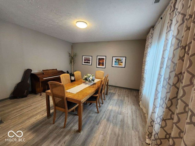 dining space featuring hardwood / wood-style flooring and a textured ceiling