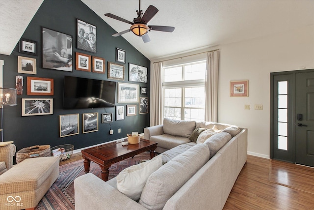 living room featuring wood-type flooring, a textured ceiling, ceiling fan, and vaulted ceiling