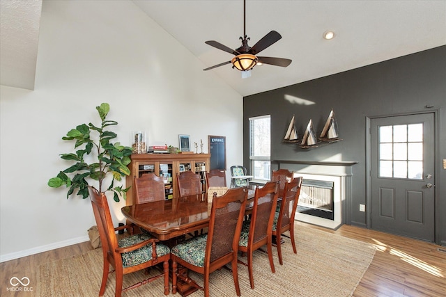 dining room featuring light hardwood / wood-style floors, ceiling fan, and high vaulted ceiling