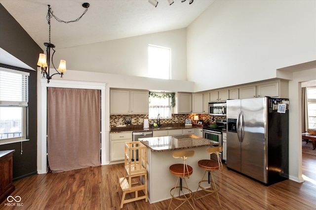 kitchen featuring stainless steel appliances, a notable chandelier, high vaulted ceiling, decorative light fixtures, and tasteful backsplash