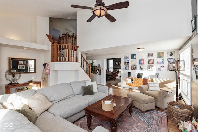 living room featuring a towering ceiling, ceiling fan, and hardwood / wood-style floors