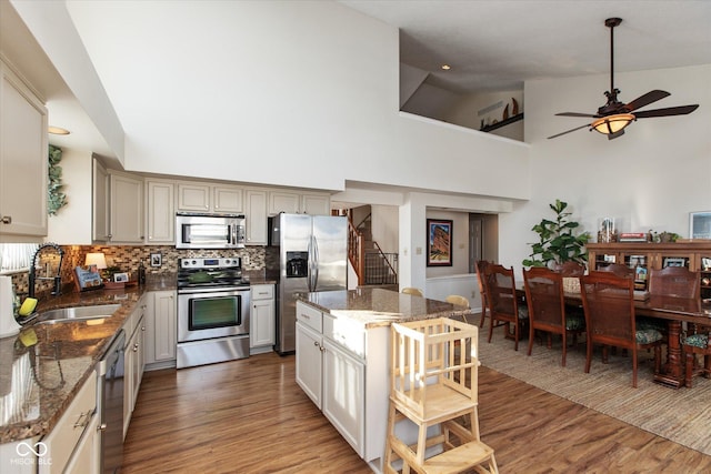 kitchen featuring stainless steel appliances, dark stone countertops, high vaulted ceiling, and sink