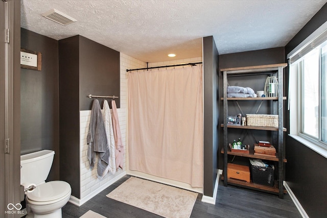 bathroom with toilet, walk in shower, a textured ceiling, and hardwood / wood-style floors