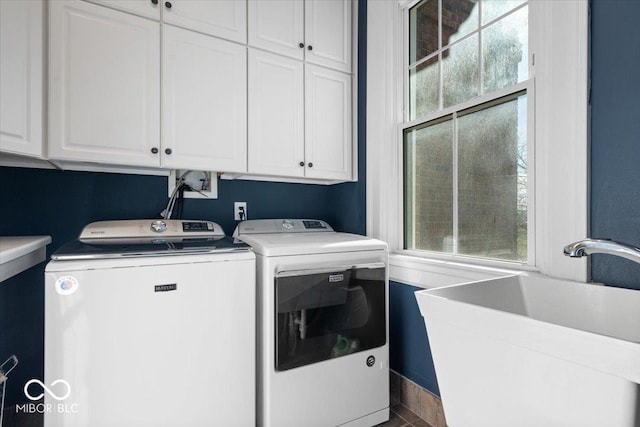 laundry area featuring cabinets, washer and clothes dryer, and sink