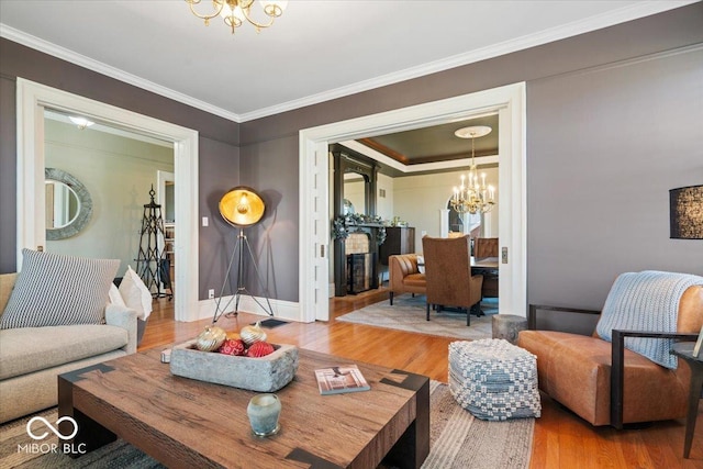 living room with ornamental molding, light hardwood / wood-style flooring, and an inviting chandelier