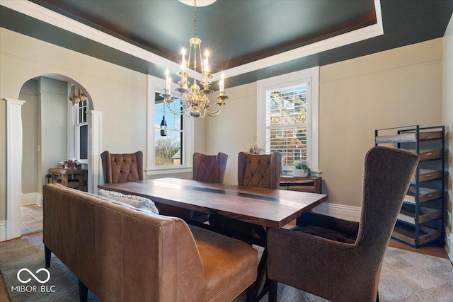 dining area featuring a notable chandelier, a tray ceiling, and plenty of natural light