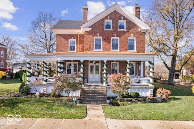 view of front of home featuring covered porch, french doors, and a front lawn