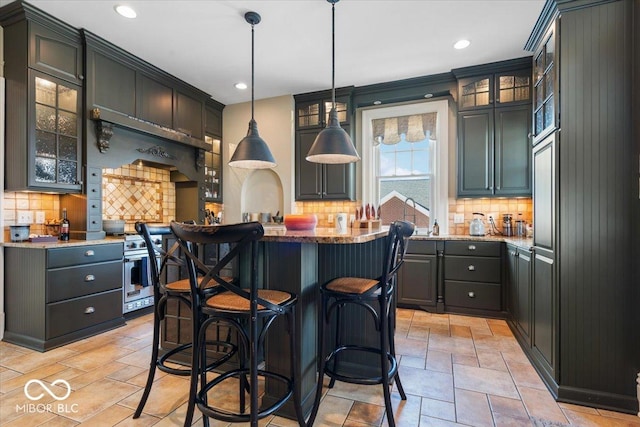 kitchen with a center island, stainless steel stove, a kitchen breakfast bar, decorative backsplash, and hanging light fixtures