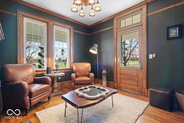 sitting room with a notable chandelier, hardwood / wood-style floors, and ornamental molding