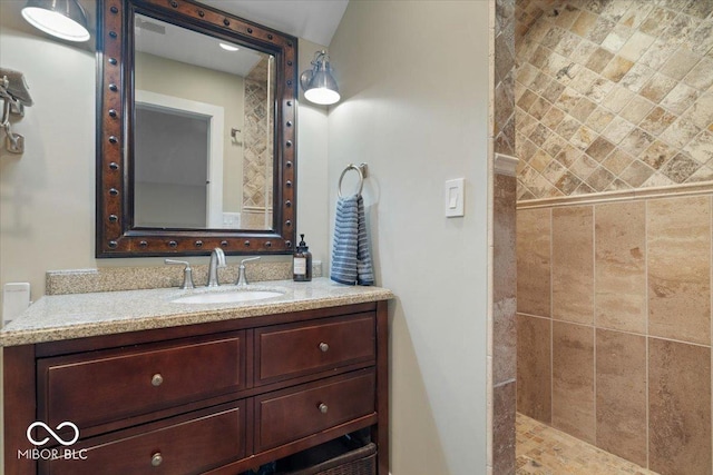 bathroom featuring a tile shower and vanity