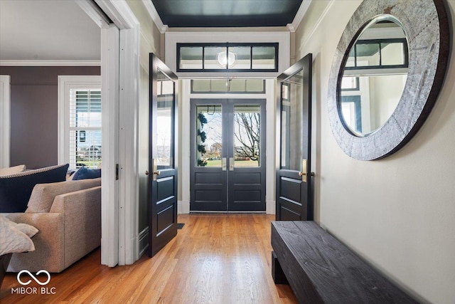 entrance foyer with ornamental molding and light hardwood / wood-style flooring