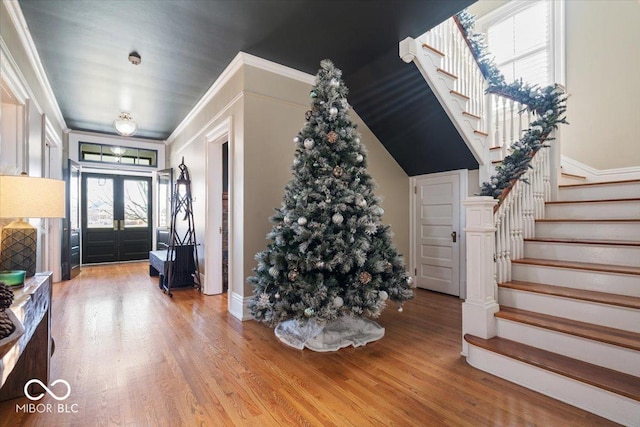 foyer featuring ornamental molding, light wood-type flooring, and french doors