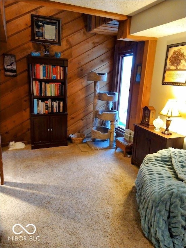 bedroom featuring wood walls, carpet floors, and a textured ceiling