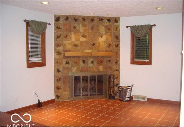 unfurnished living room featuring tile patterned flooring, a textured ceiling, and a large fireplace