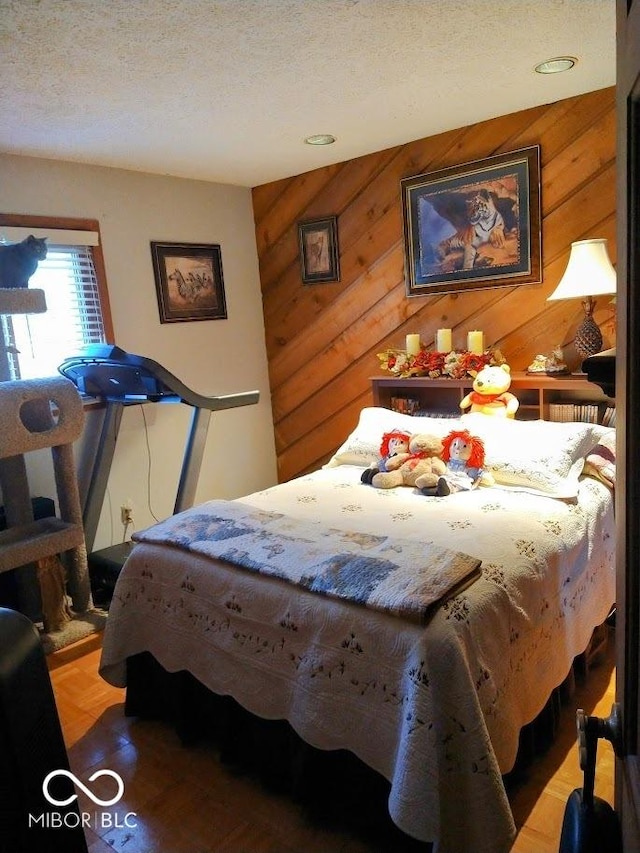 bedroom featuring parquet flooring, a textured ceiling, and wood walls