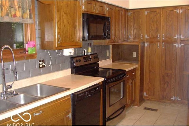 kitchen with backsplash, sink, light tile patterned floors, and black appliances