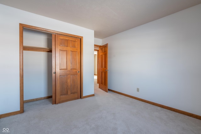 unfurnished bedroom with a closet and light colored carpet