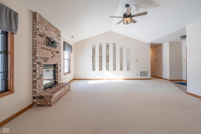 unfurnished living room with lofted ceiling, a brick fireplace, light colored carpet, and ceiling fan