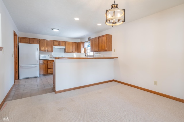 kitchen featuring white appliances, kitchen peninsula, a chandelier, pendant lighting, and light colored carpet