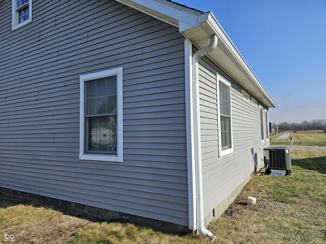 view of side of property featuring central AC and a lawn