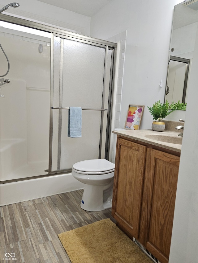 bathroom with vanity, hardwood / wood-style flooring, a shower with shower door, and toilet