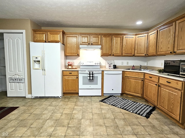 kitchen featuring sink, a textured ceiling, and white appliances